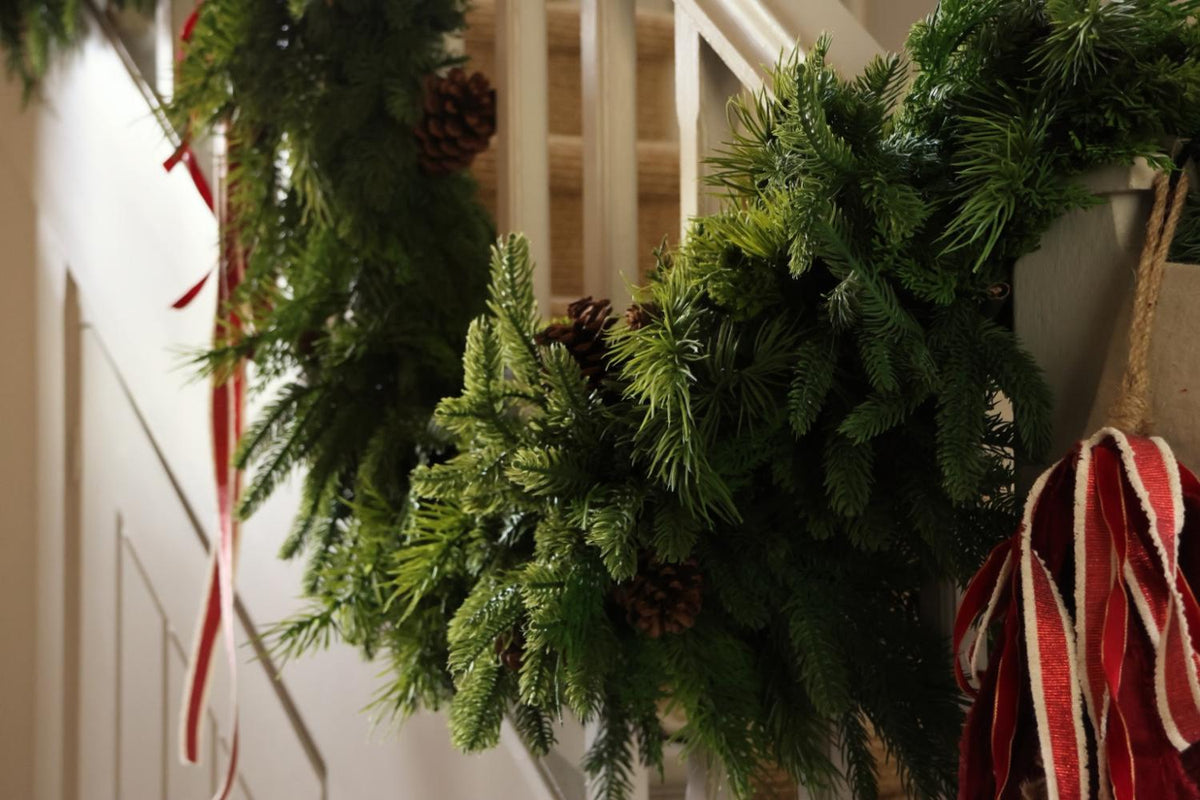 An Artificial green foliage garland on a staircase with red ribbon 