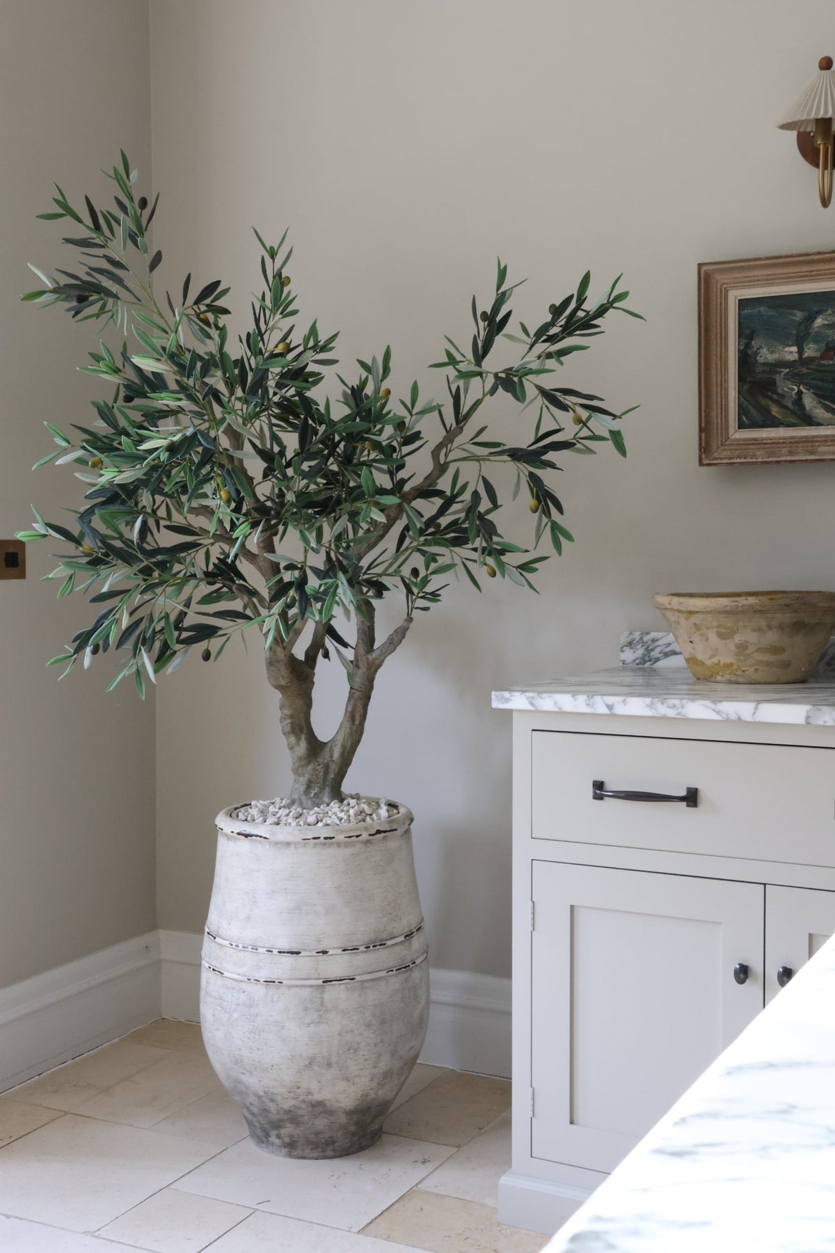 artificial olive tree in large stone planter in a kitchen