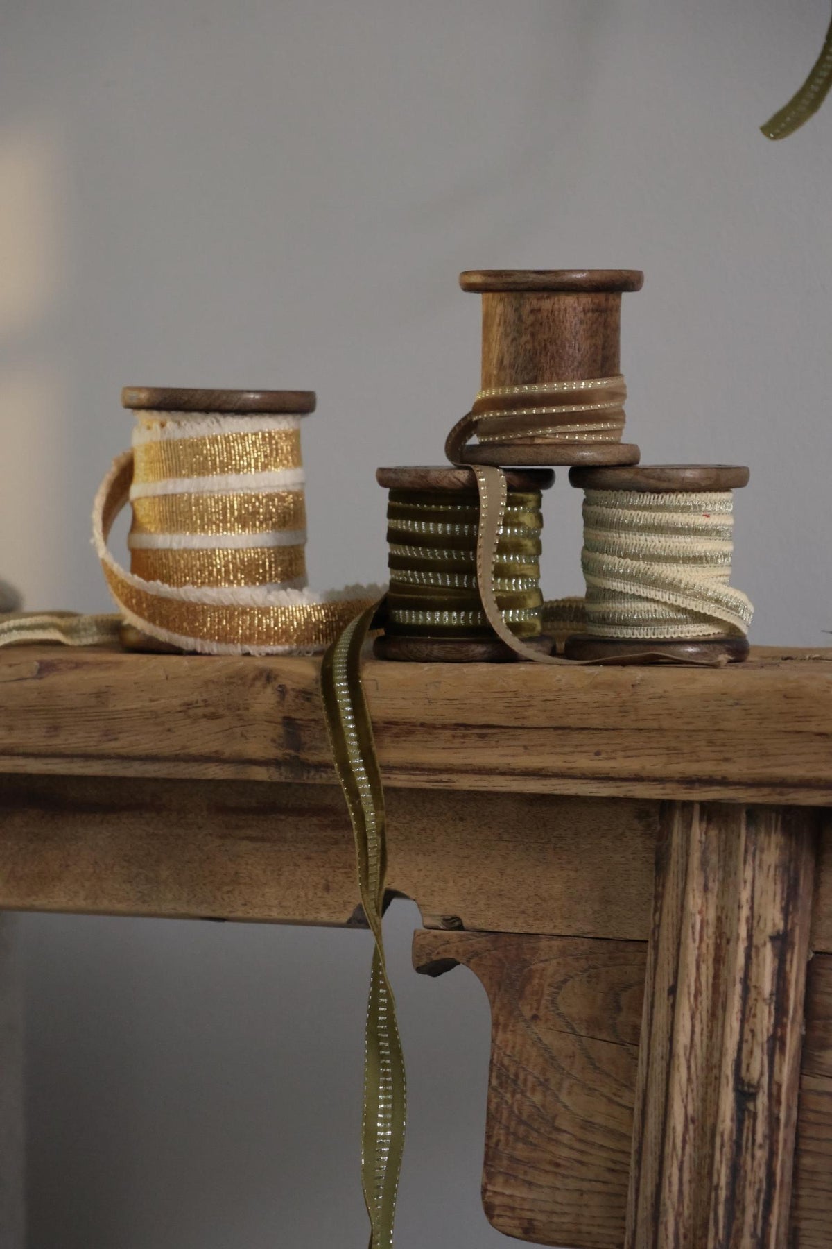 Collection of ribbons on wooden spools stacked on an antique wooden bench 