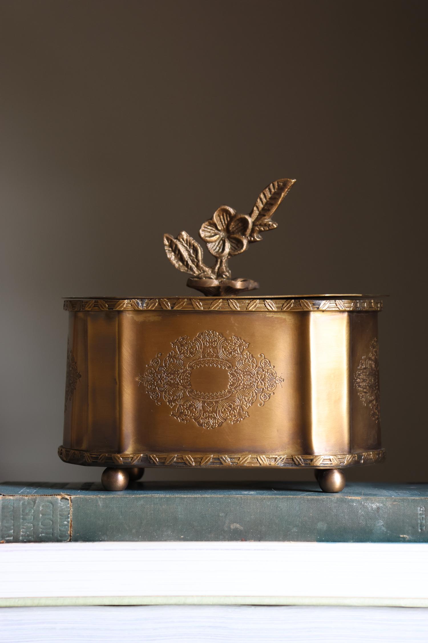 Decorative brass box with floral design on a dark surface