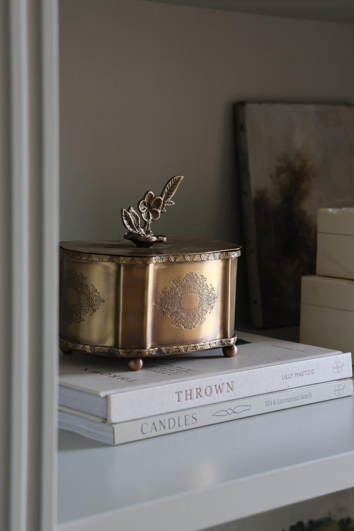 Decorative brass box on top of books with a neutral background