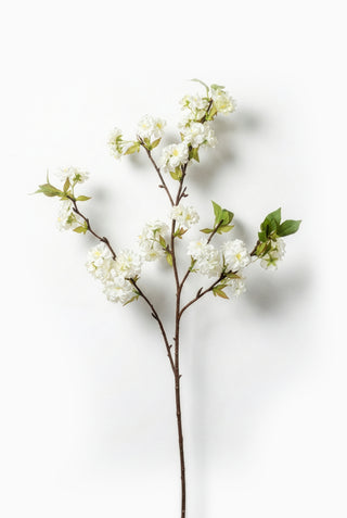 Artificial flower branch with white flowers and green leaves on a white background