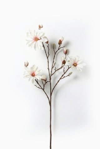 Artificial magnolia branch with white and pink flowers on a white background