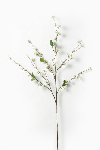Artificial blossom branch with small green leaves and buds on a white background