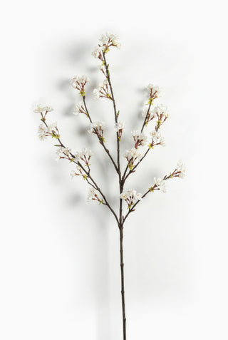 Artificial cherry blossom branch with white flowers on a white background
