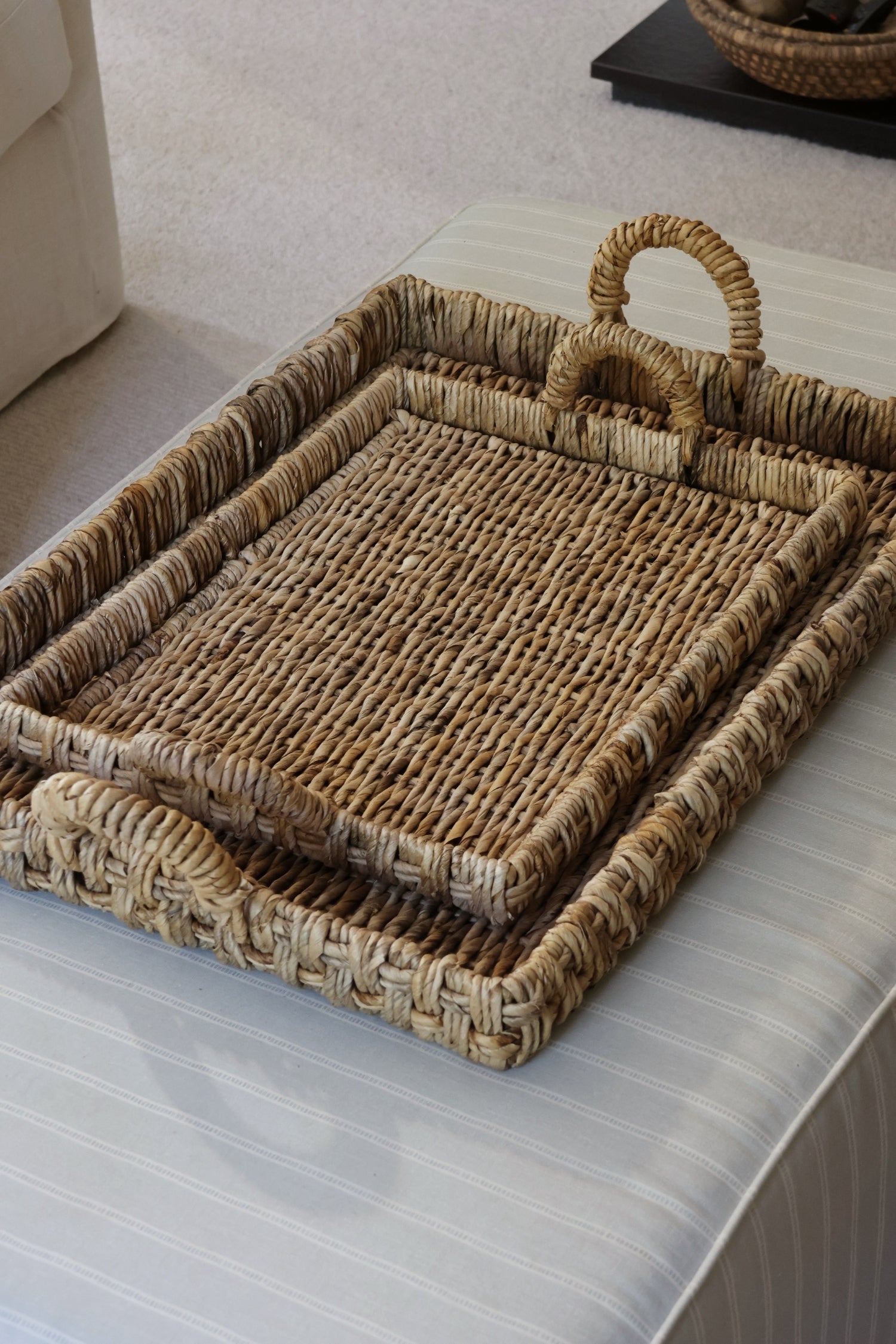 Nested woven banana bark trays on ottoman 