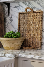 Rectangular banana bark tray standing up against marble kitchen backplash 