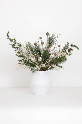 Decorative artificial flower arrangement in a white vase on a white background