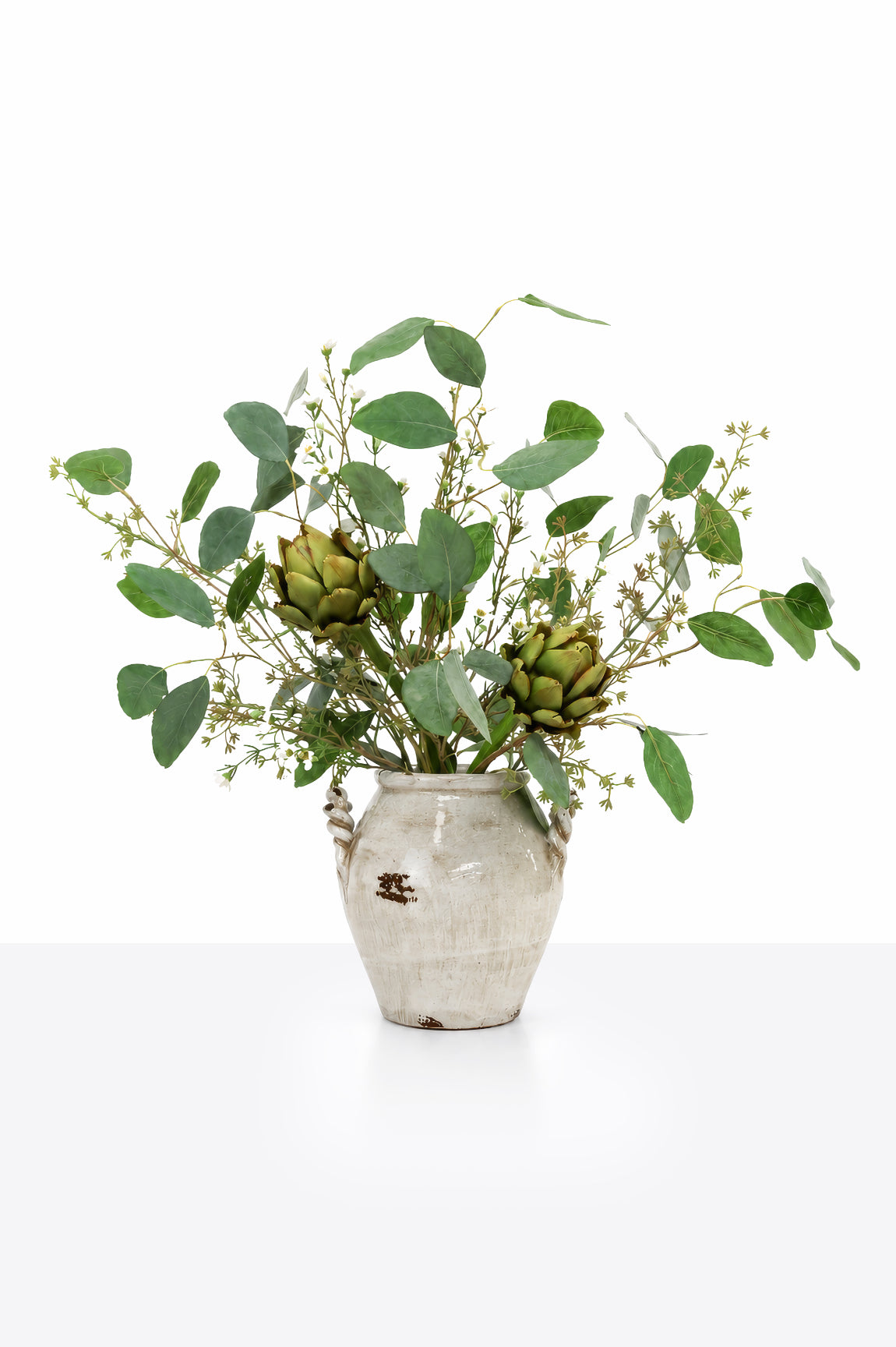 Medium sized artificial faux Artichoke Arrangement with green eucalyptus, seeded stem, artichoked in a white rustic ceramic vase on a white background