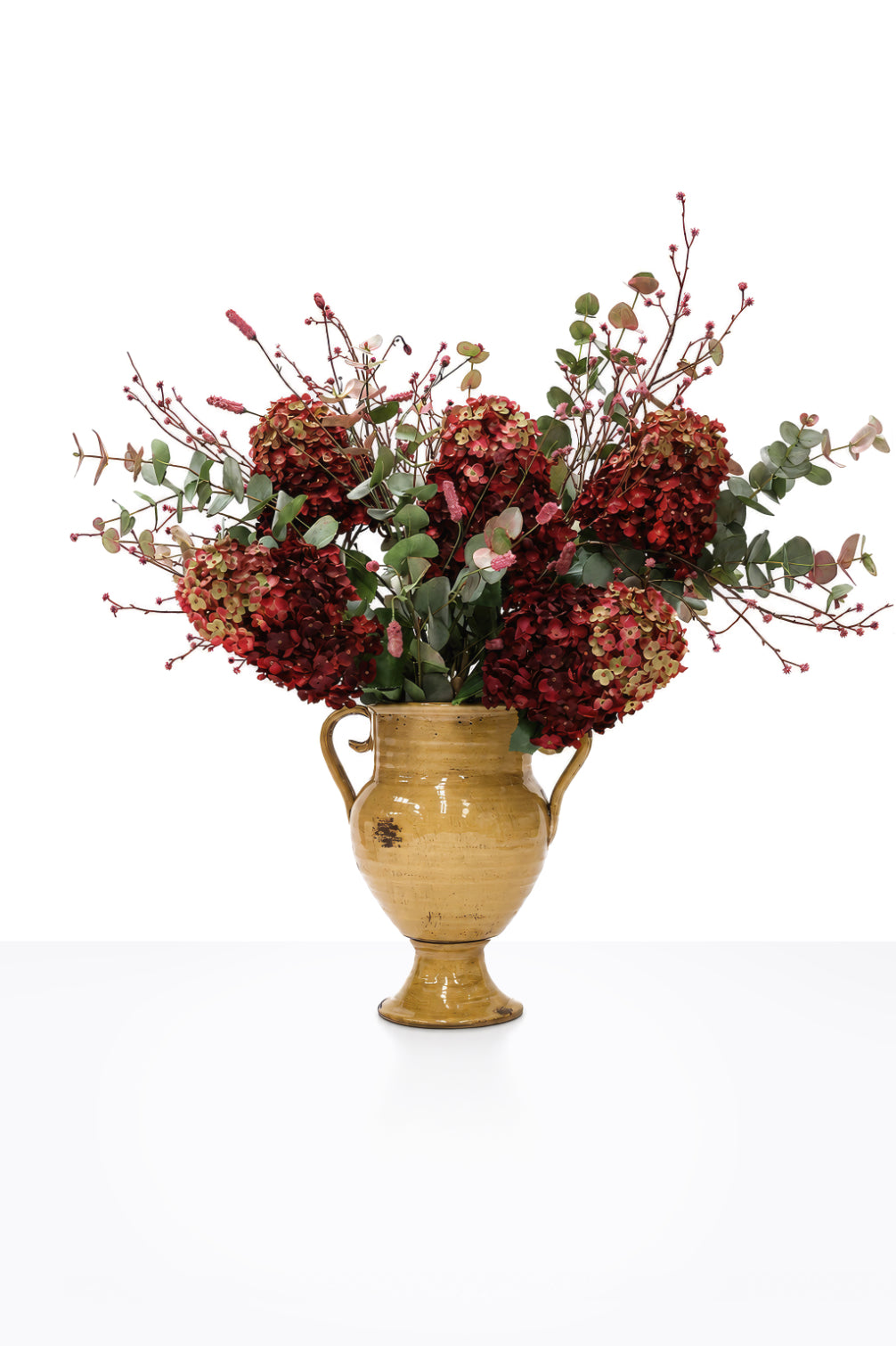 Artificial Autumn Crimson Hydrangea Arrangement in a mustard ceramic urn on white background