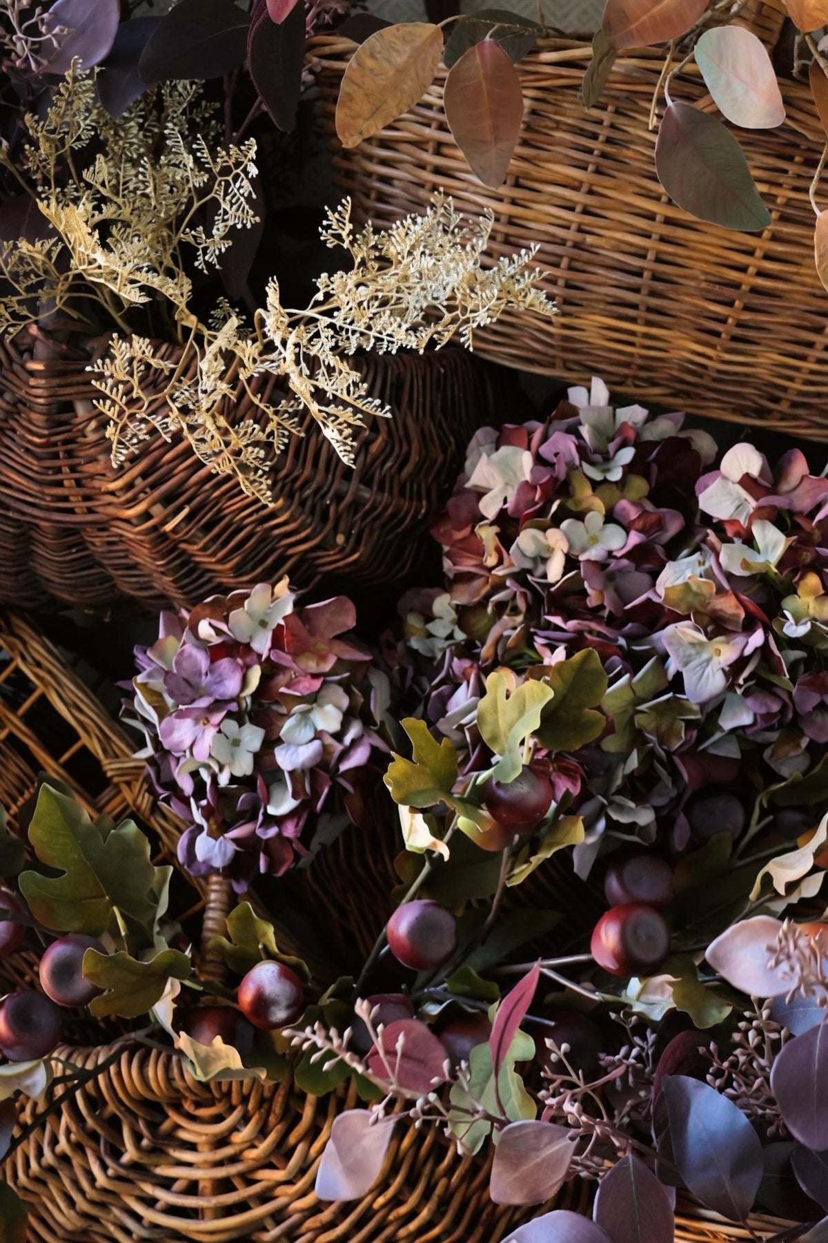 vintage wicker baskets with artificial autumn burgundy stems artistically styled 