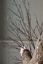 Brown artificial branches and twigs being arranged by a womens hand with blurred background 