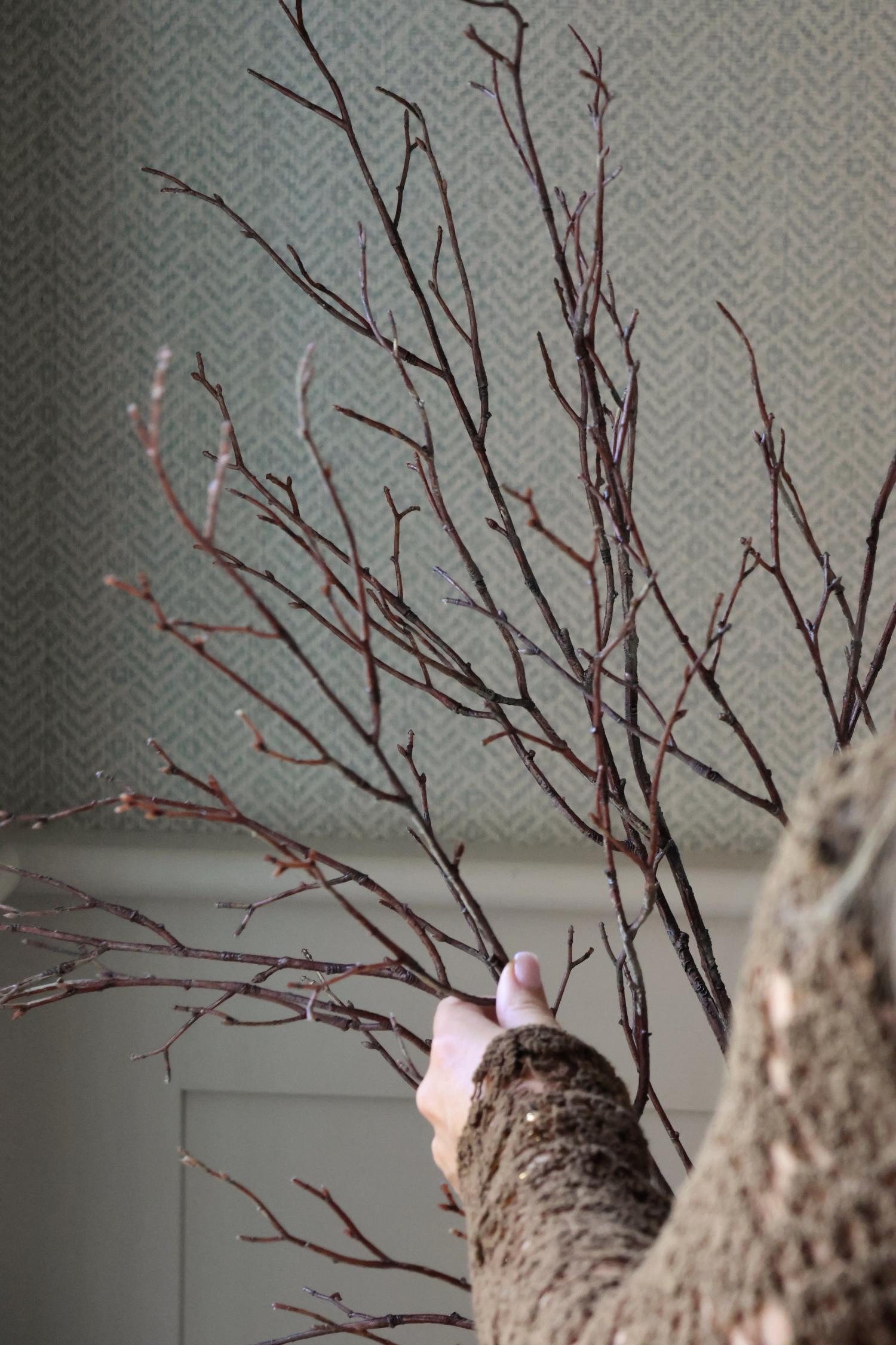 Brown artificial branches and twigs being arranged by a womens hand with blurred background 
