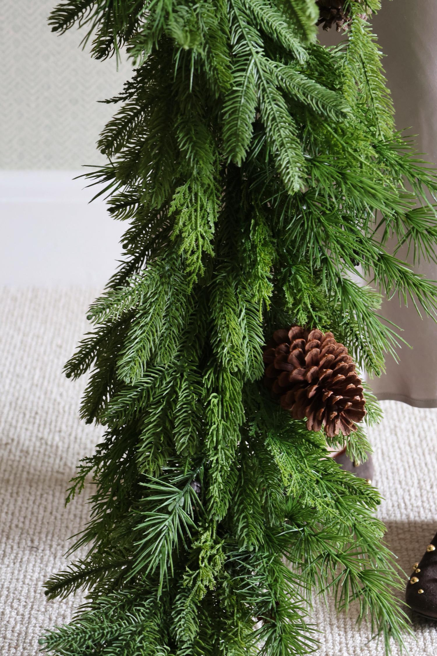 Artificial green garland with a pine cone on a neutral background