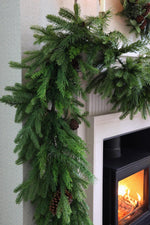 Green faux Christmas garland hanging above a fireplace with a visible fire.