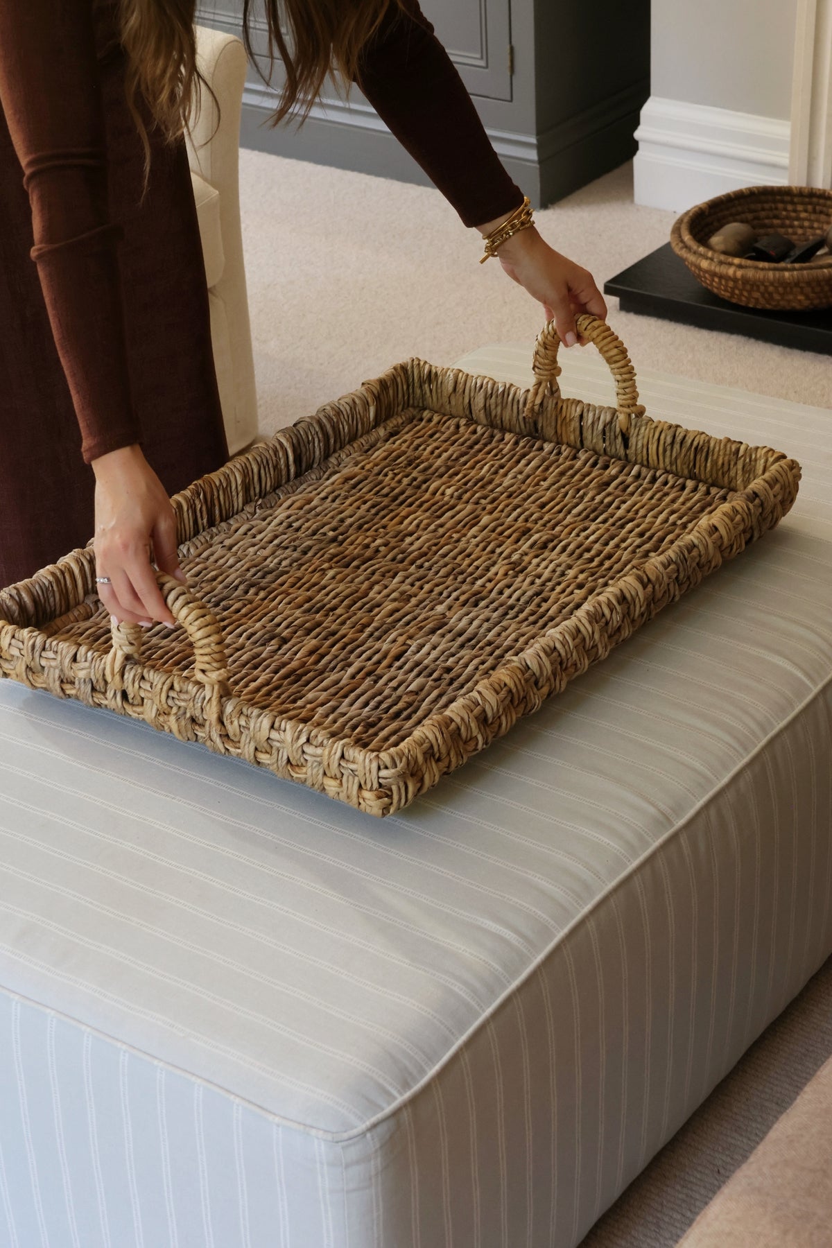 Large coffee table styling woven tray on an ottoman in lounge setting 