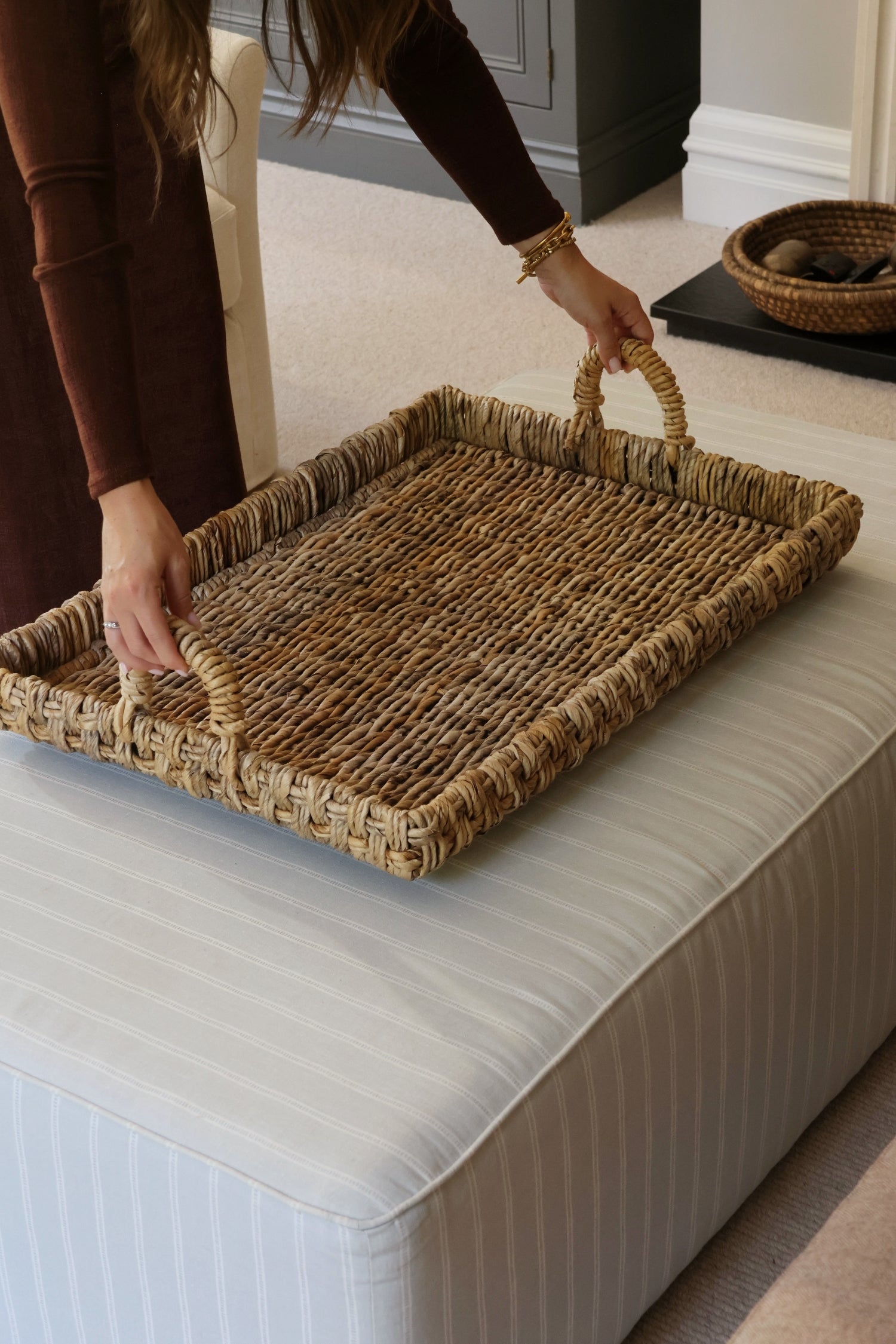 Large coffee table styling woven tray on an ottoman in lounge setting 