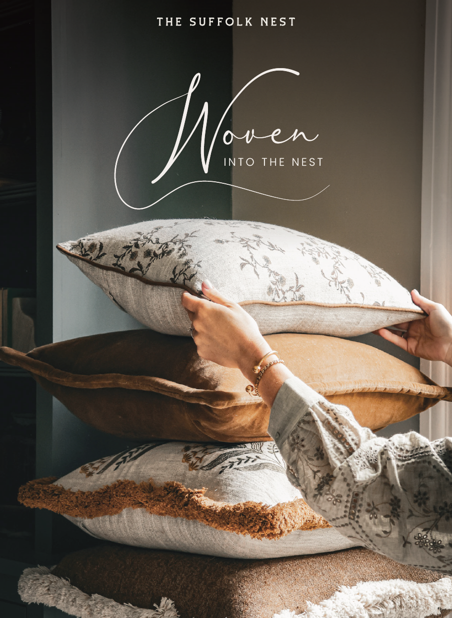 Person holding a pile of cushions with 'The Suffolk Nest' branding, featuring woven textures.