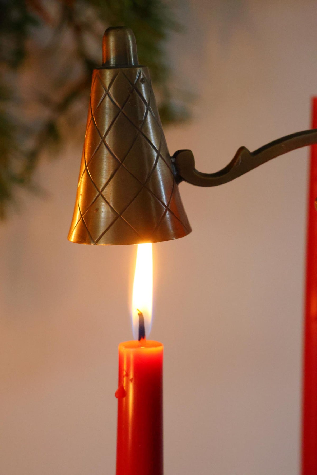 Brass Candle Snuffer ontop of a lit candle flame with blurred background