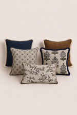Set of four decorative cushions with various patterns and textures on a light background