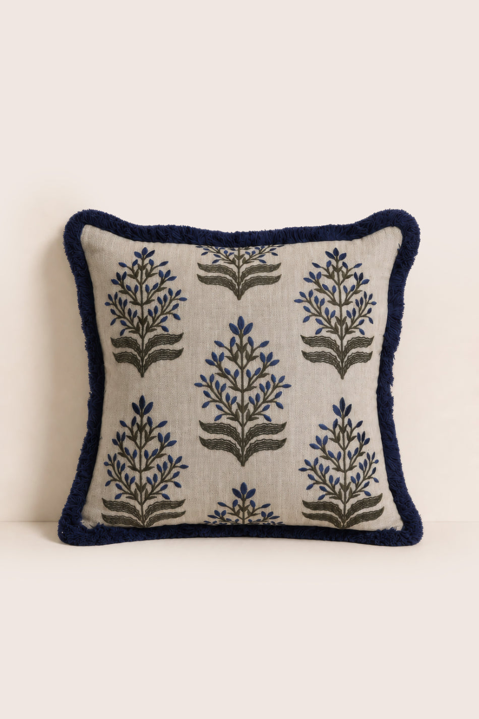 Decorative pillow with floral patterns and navy border on a beige background