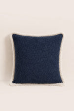 Navy blue pillow with white trim on a beige background