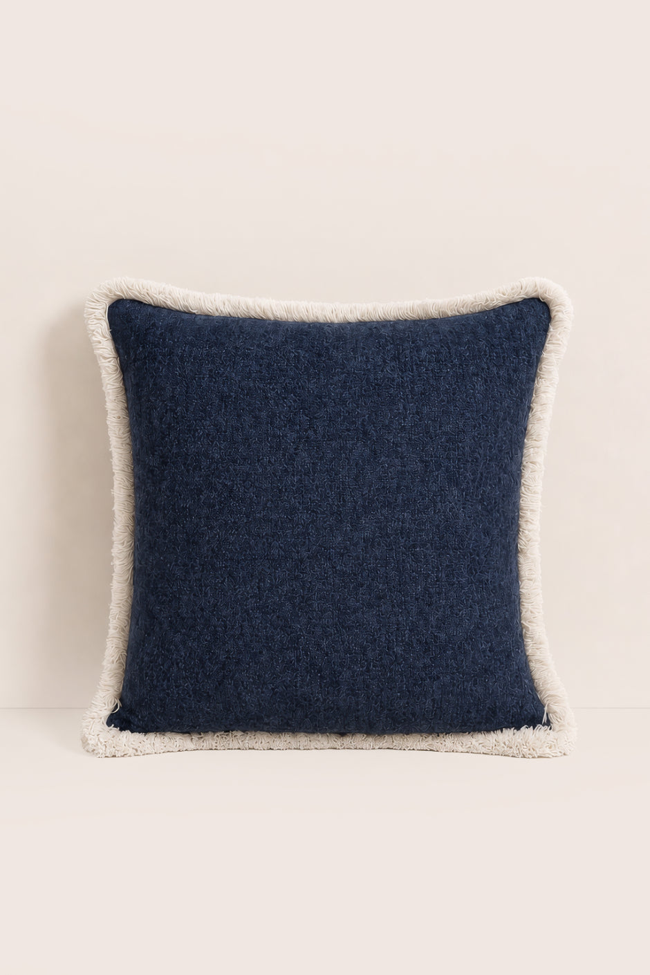 Navy blue pillow with white trim on a beige background