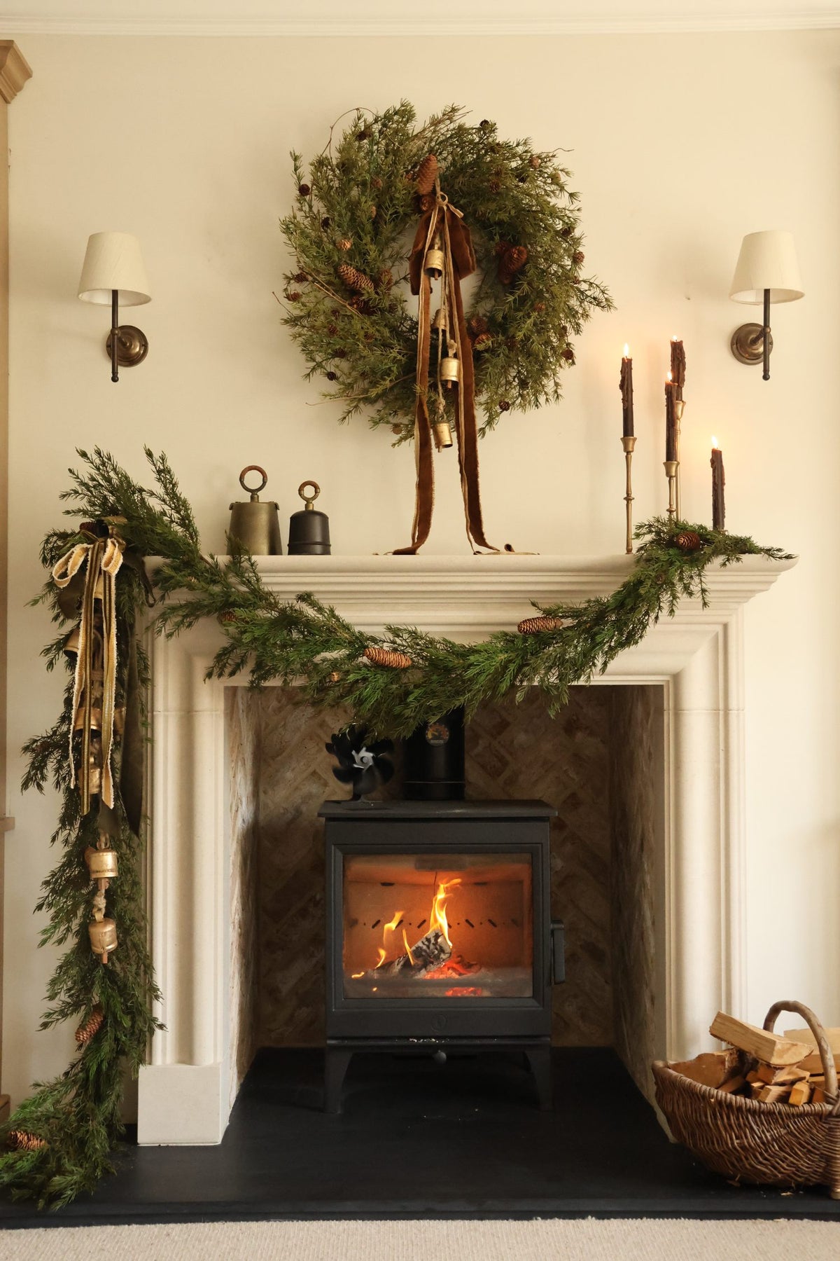 Faux nordic wreath and larix garlands styled on a limestone fire surround with log burner in a cosy living room 