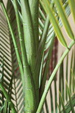 Close-up of green faux palm leaves and trunk with a blurred background
