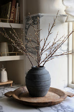 A faux willow spray with lifelike off-white buds on varying sized branches, arranged in a rustic style vase.