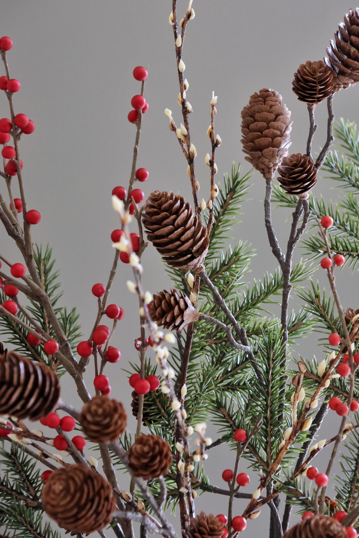 Decorative arrangement with pine cones, red berries, and greenery on a gray background