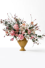 Large pink faux floral arrangement in a yellow vase on a white background
