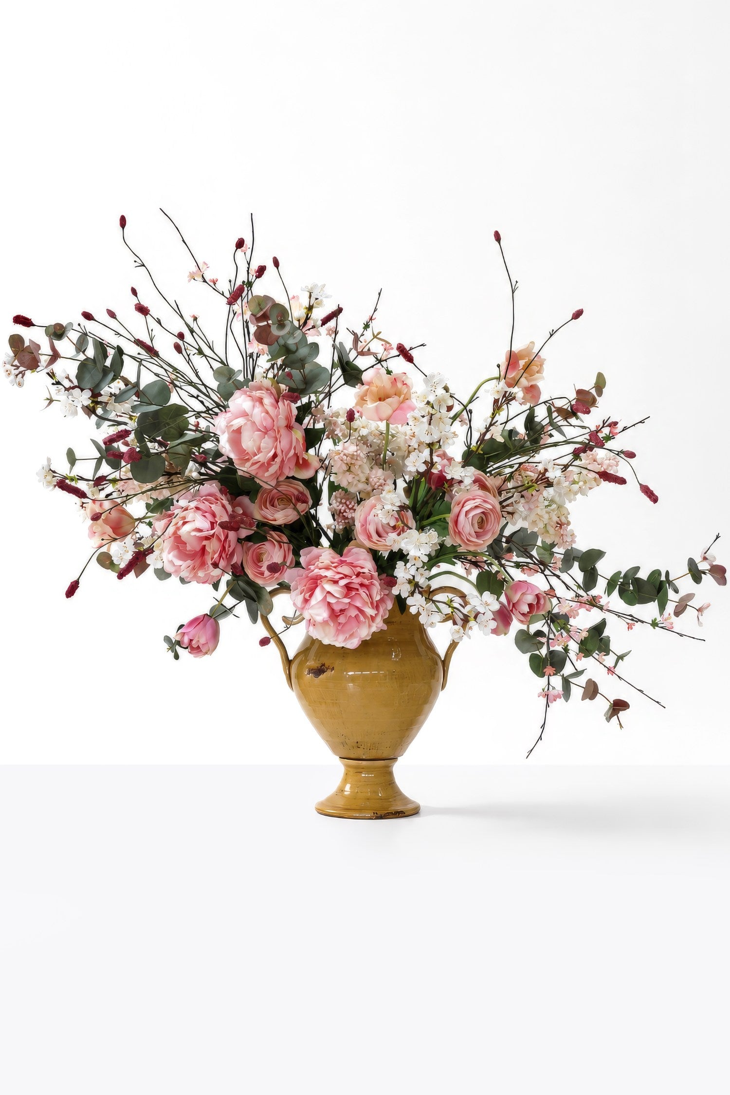 Large pink faux floral arrangement in a yellow vase on a white background