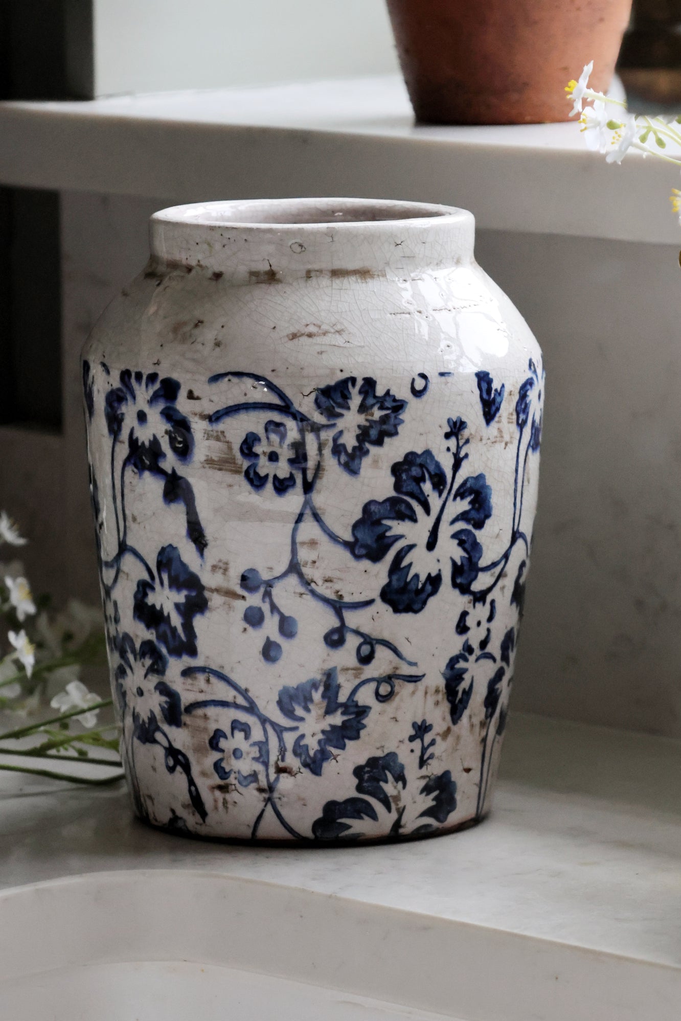 White ceramic vase with blue floral patterns on a shelf