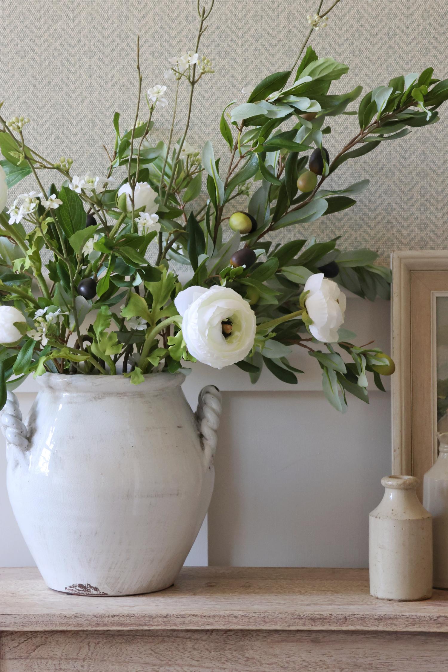 Floral arrangement in a white vase on a wooden surface with a neutral background
