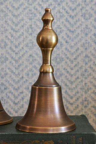Bronze bell on a textured surface with a patterned background