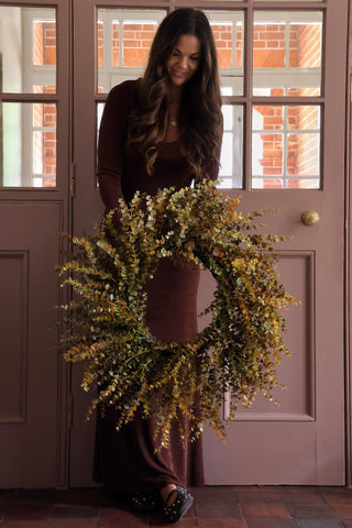 Woman holding a wreath in front of a door