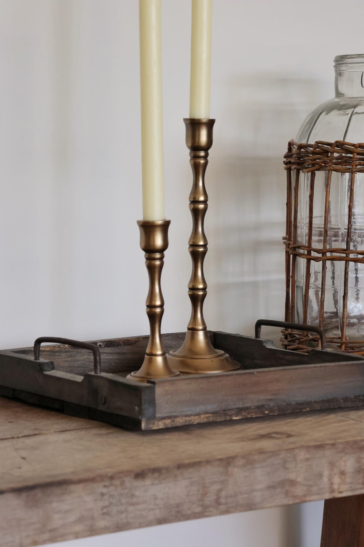 two brass candlesticks with candles on a wooden surface