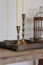 two brass candlesticks with candles on a wooden surface