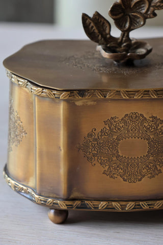 Decorative brass box with intricate engravings on a light background