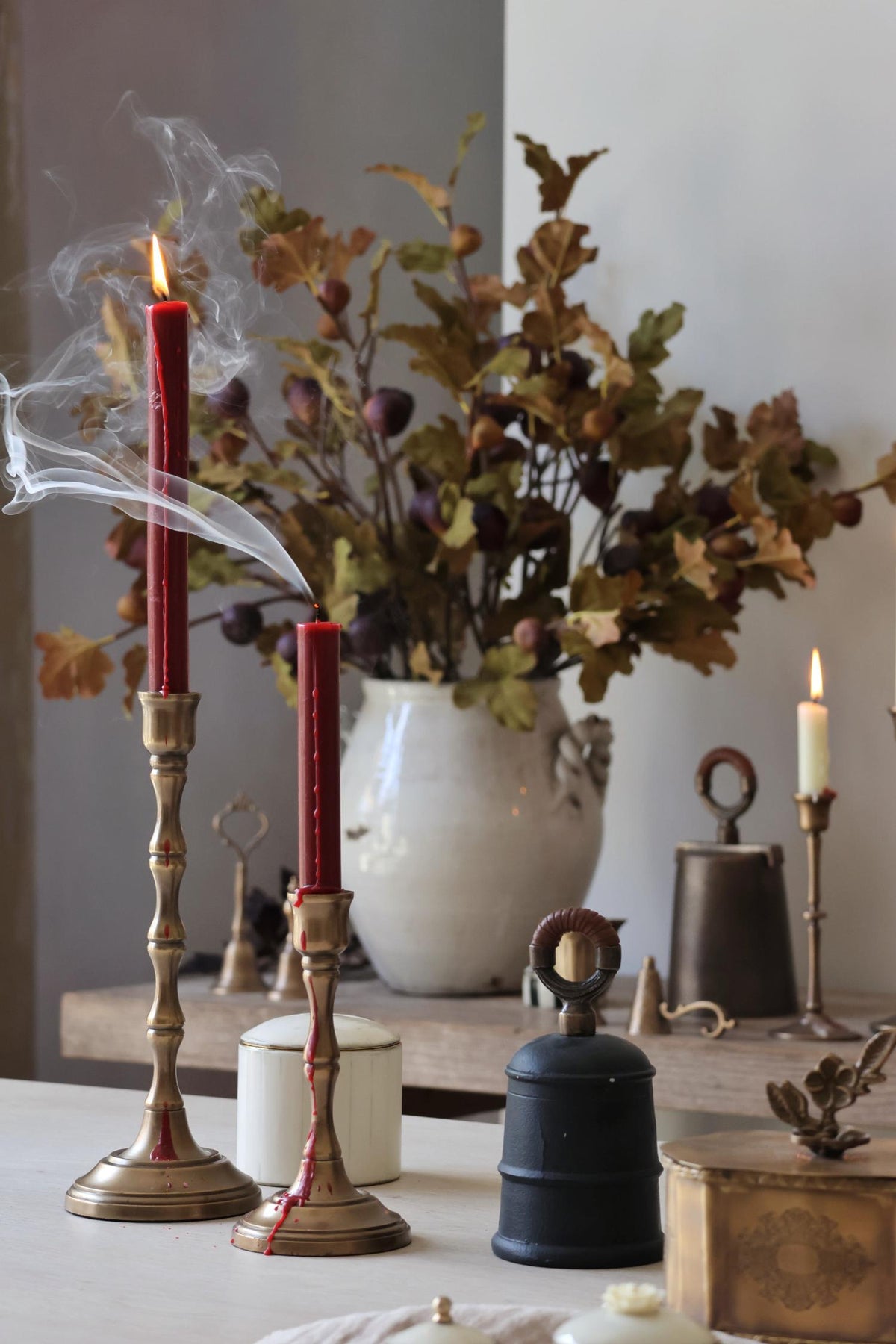 Decorative setup with candles, a vase of flowers, and various objects on a table.