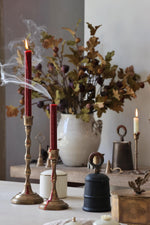 Decorative setup with candles, a vase of flowers, and various objects on a table.