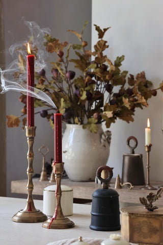 Decorative setup with candles, a vase of flowers, and various objects on a table.
