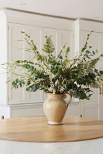 Vase with greenery on a wooden table in a kitchen setting