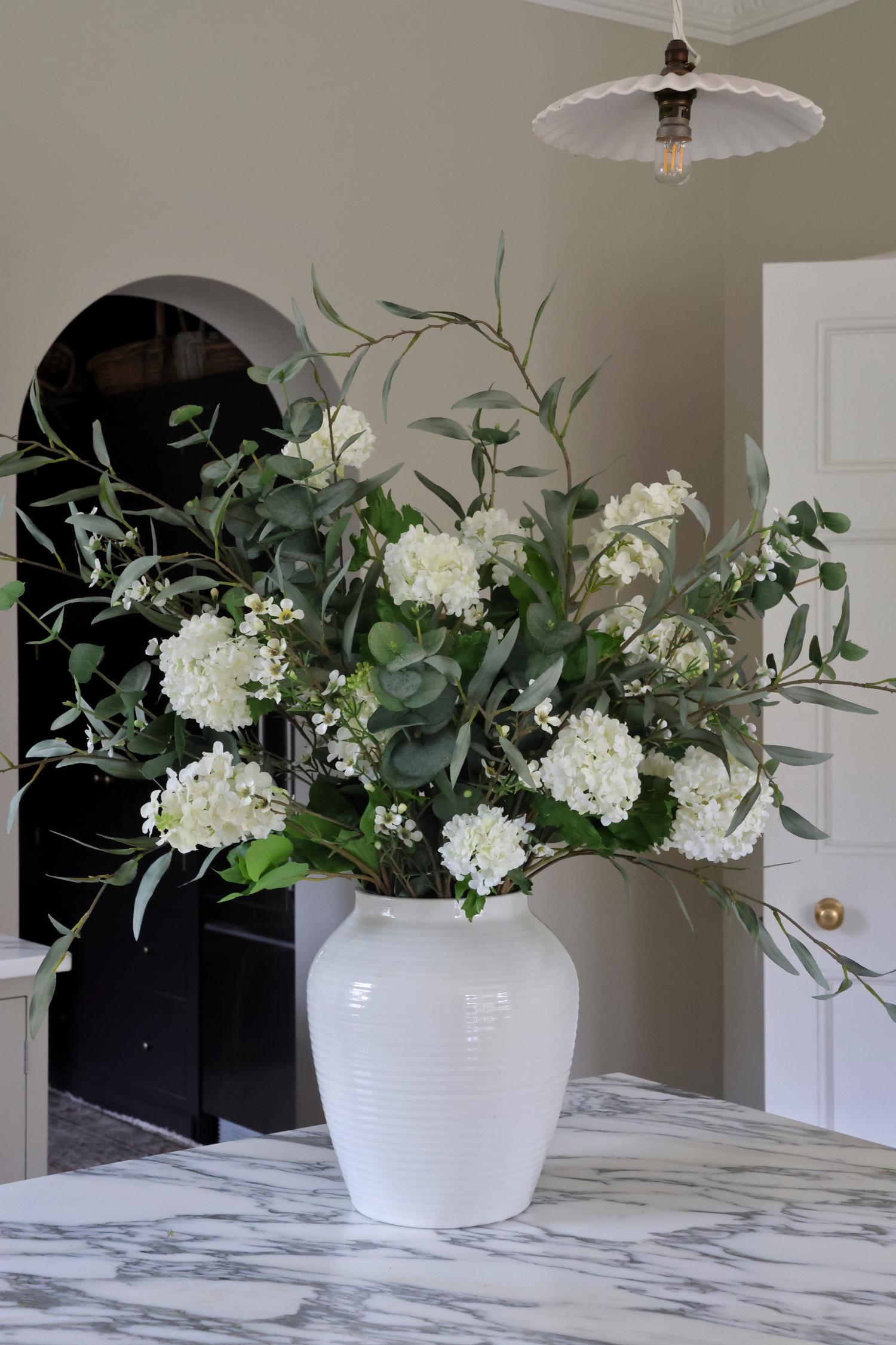 Lavenham Vase on marble worktop with green and white faux flower arrangement 