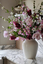 Vase of flowers on a marble countertop with a neutral background