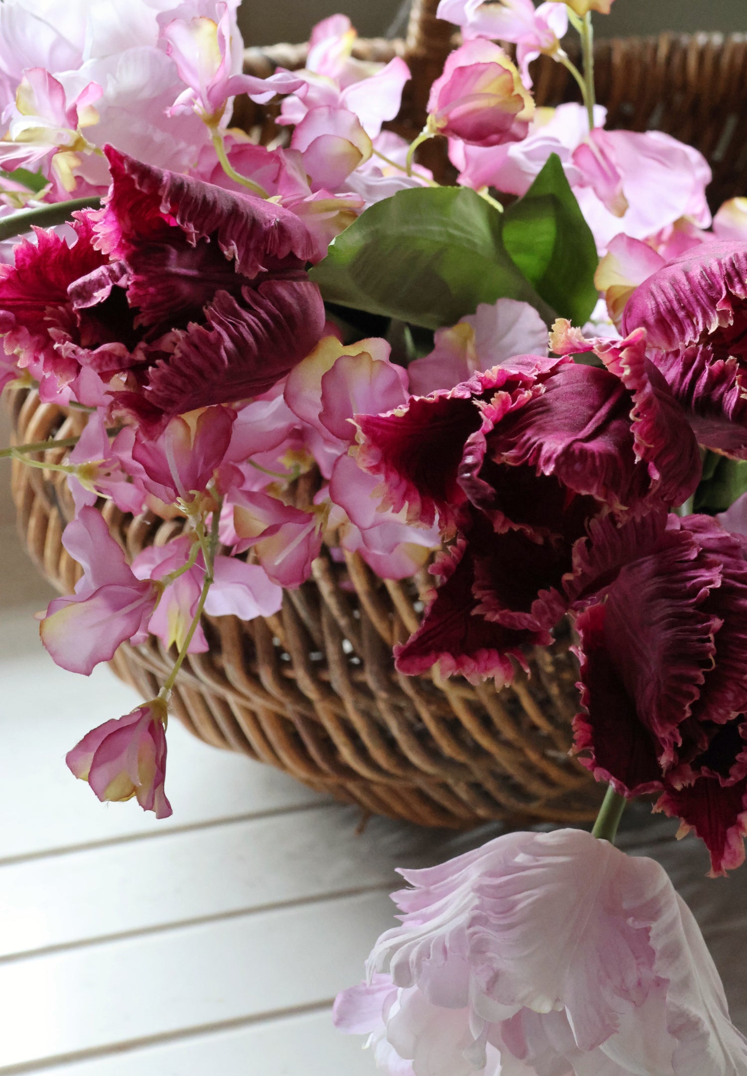 Basket filled with pink and purple flowers on a white surface