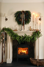 Styled christmas mantle scene with faux garlands and wreaths and brass candlesticks 