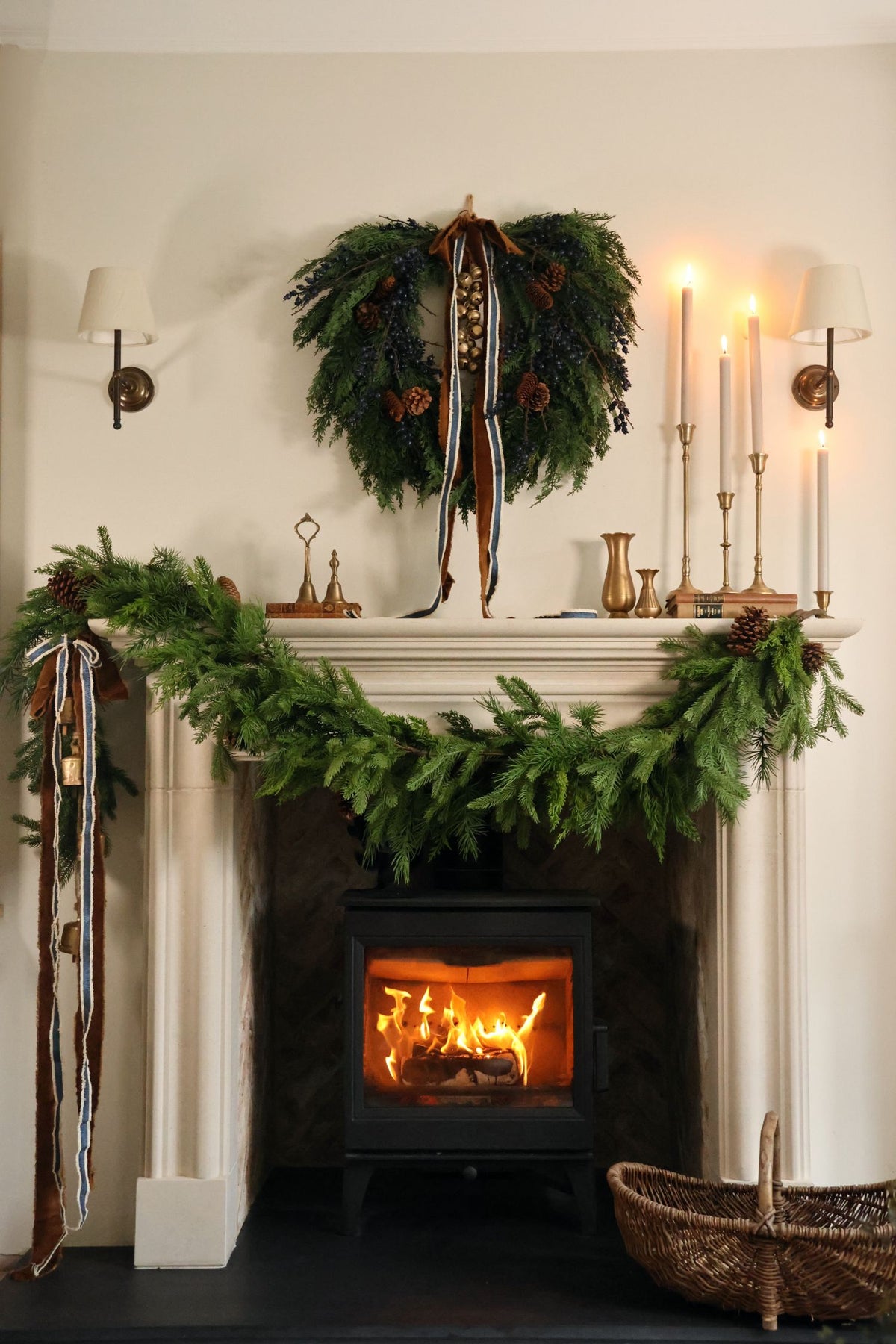 Styled christmas mantle scene with faux garlands and wreaths and brass candlesticks 