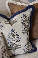 Decorative cushion with embroidered floral pattern and fringe on a couch